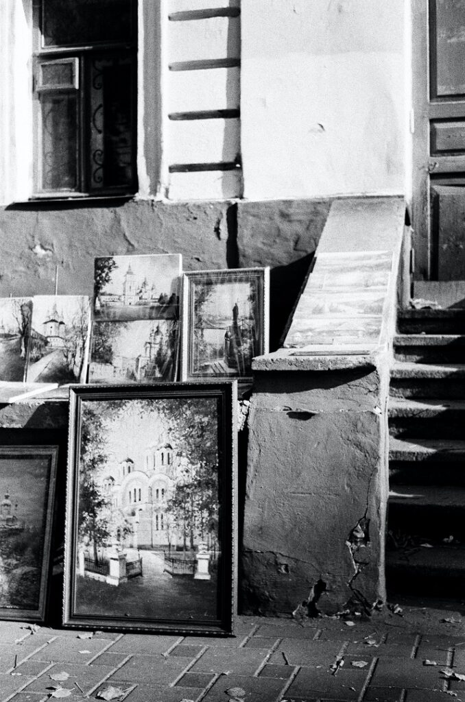 Cuadros apilados ante un edificio. Blanco y negro.