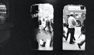 Gente en la calle tras las cristaleras de las puertas de un local. En blanco y negro.