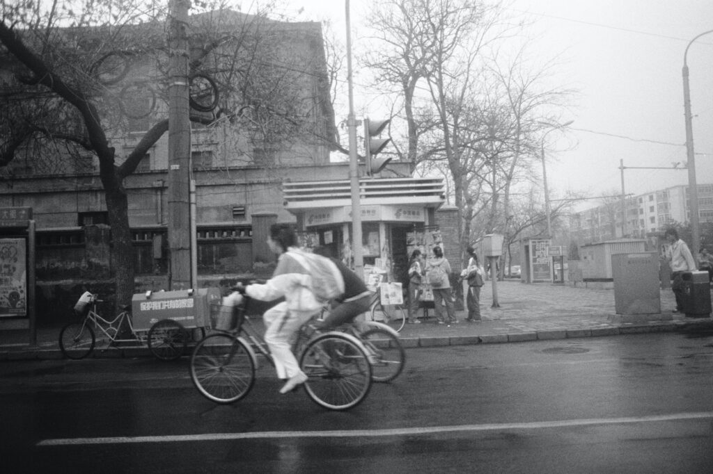 Ciclistas con chubasquero en una calle húmeda.