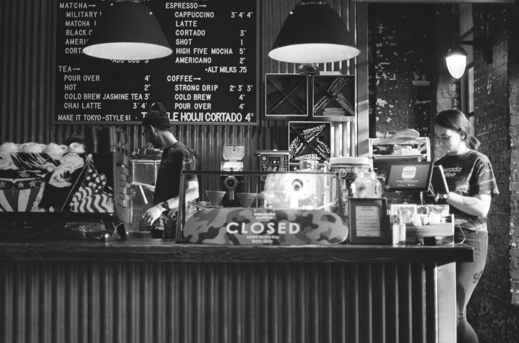 Una pareja trabaja en el mostrador de una cafetería. Blanco y negro.