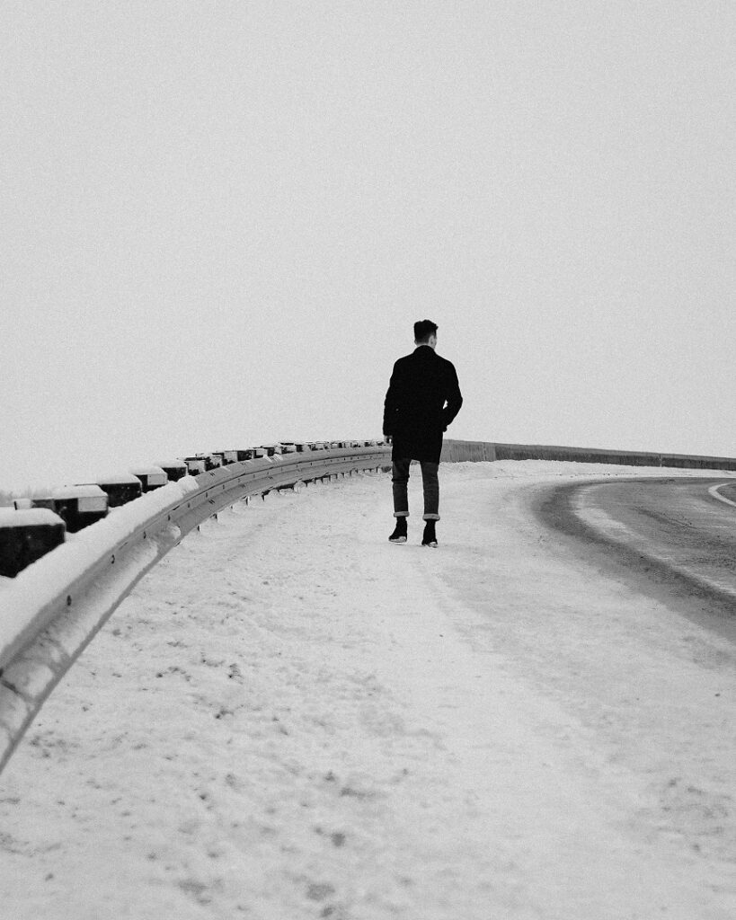 Un hombre perdido en una carretera nevada. Blanco y negro.