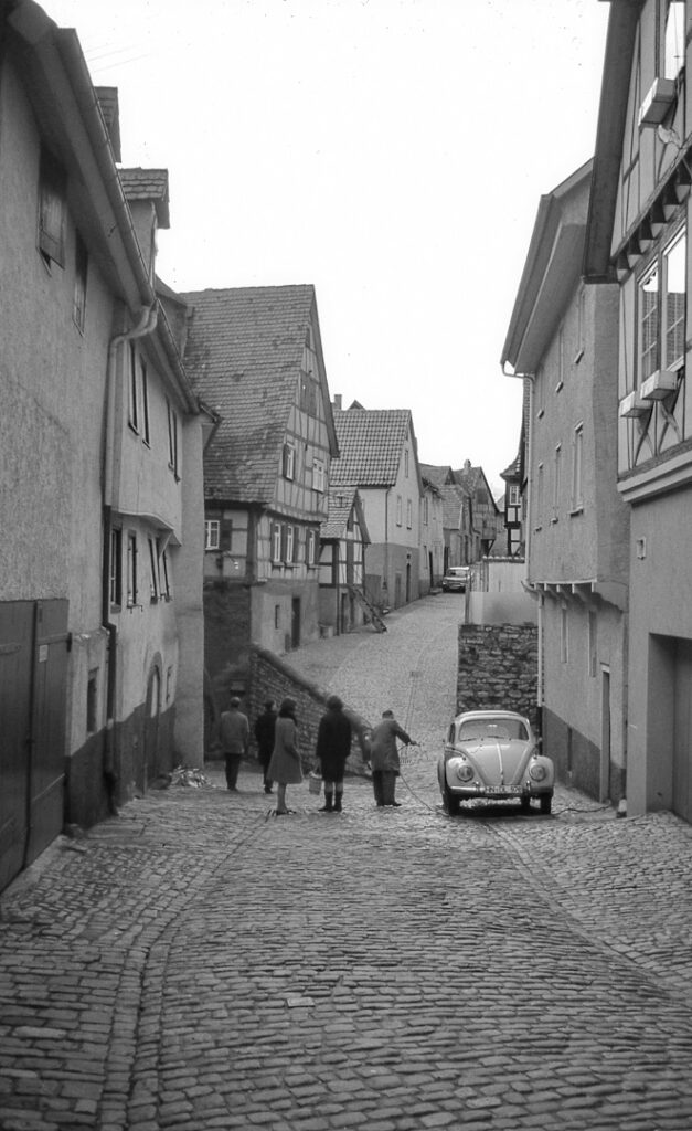 Una calle de un pueblo y gente a lo lejos. Blanco y negro.