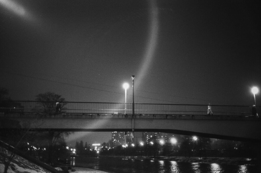 Un puente en la noche y el reflejo de una farola. Blanco y negro.